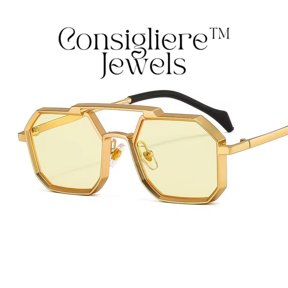 The Consigliere™ Jewels Luxury Sunglasses are high-quality unisex sunglasses with a stylish gold metal frame and polycarbonate lenses. These polygonal sunglasses feature laser engraved branding of the "Consigliere™" name, adding a personalized touch to the design. With a retro 80s and 90s theme, these sunglasses are sure to make a statement and provide both style and protection for any fashion-forward individual.