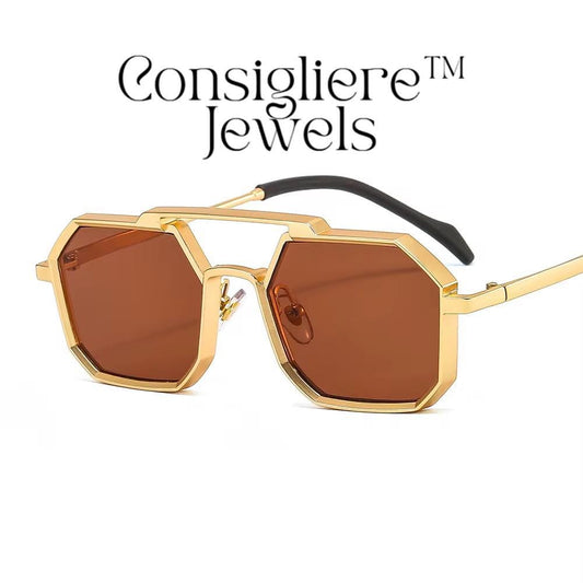 The Consigliere™ Jewels Luxury Sunglasses are high-quality unisex sunglasses with a stylish gold metal frame and polycarbonate lenses. These polygonal sunglasses feature laser engraved branding of the "Consigliere™" name, adding a personalized touch to the design. With a retro 80s and 90s theme, these sunglasses are sure to make a statement and provide both style and protection for any fashion-forward individual.